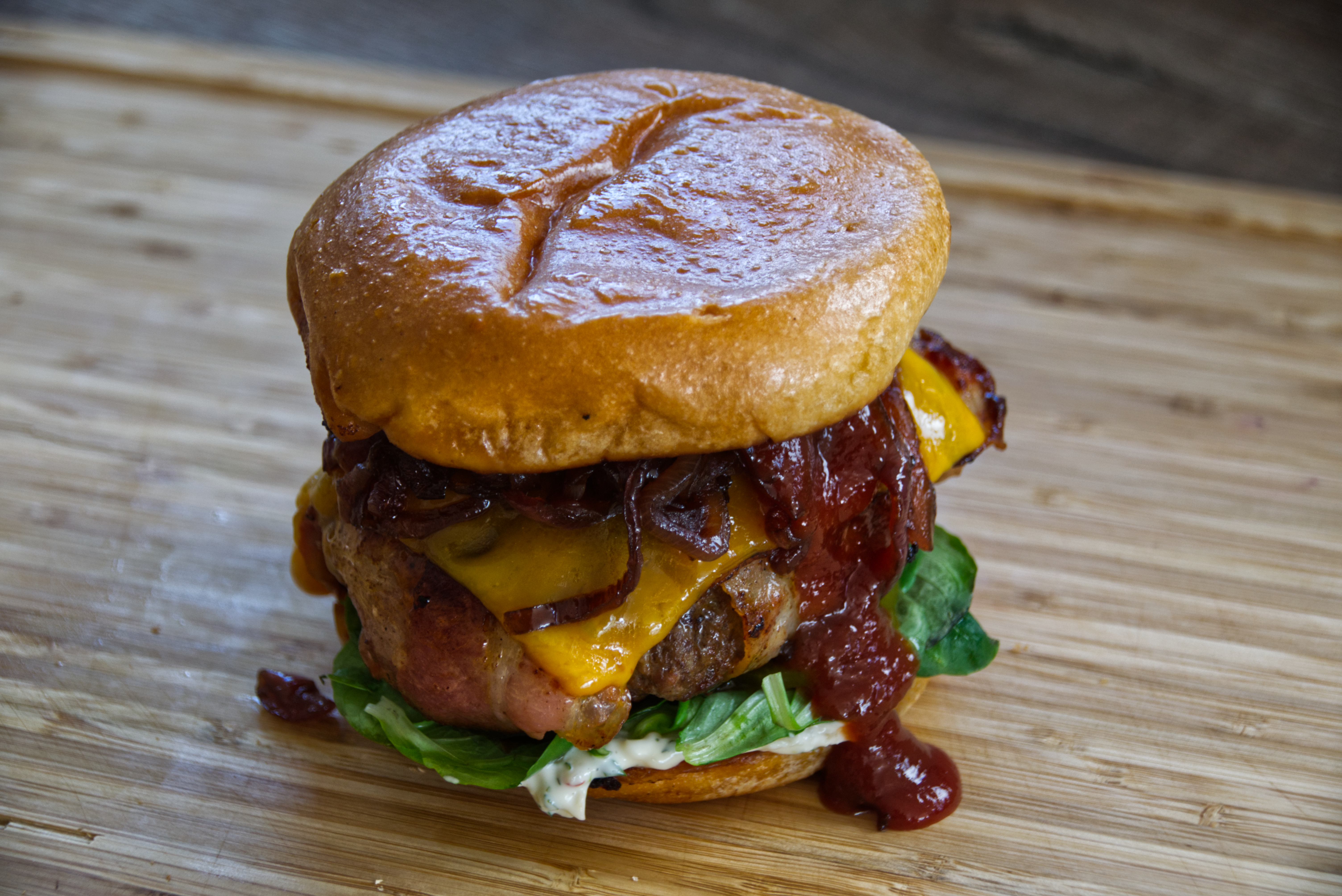 Cheddar Bacon Bomb Burger with Apple-Tarragon Mayonnaise, BBQ Sauce and Balsamic Onions.